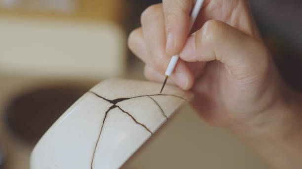 Woman repairing broken pottery. Kintsugi.