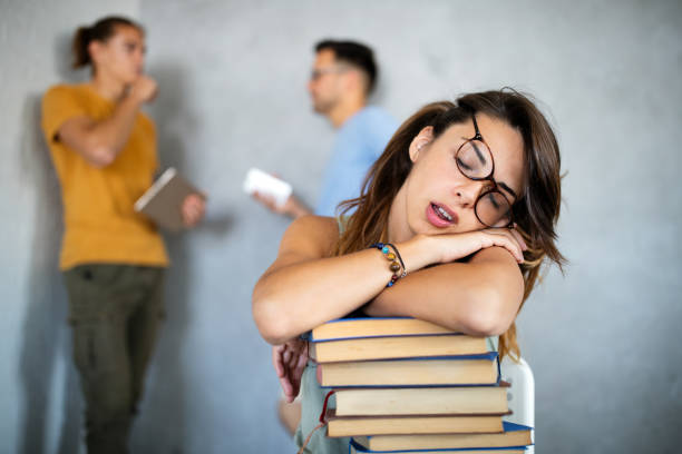 istock Tired female student sleeping on the books in the library 1330540496