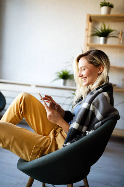 istock Relaxed young woman in sofa smiling content, happy and reading, working on tablet pc at home 1330541306