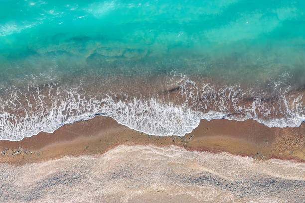 istock Sea waves breaking on a sand shore, top view directly above 1330545322