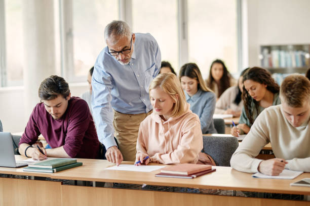 istock Mature teacher assisting his student during class at college classroom. 1330545896