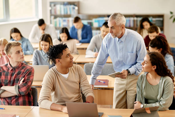 istock Senior teacher talking to his students at university classroom. 1330545960
