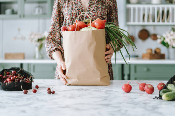 mulher segurando saco de supermercado de papel com legumes - green consumerism bag paper bag - fotografias e filmes do acervo