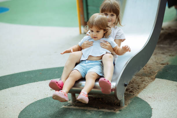 istock Girls playing outside in summer on slide 1330548587
