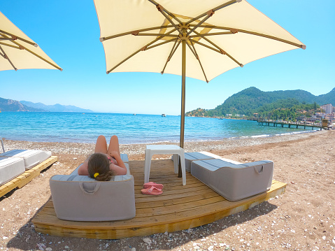 Cute little girl rest on a sun lounger beach chair