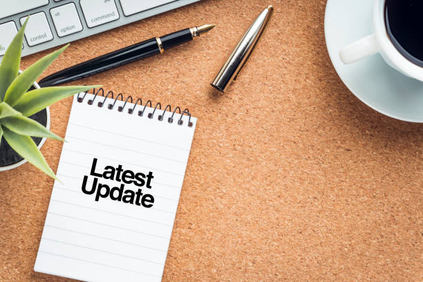 istock LATEST UPDATE text with notepad, decorative plant, keyboard, coffee cup and fountain pen on wooden background. 1330550711