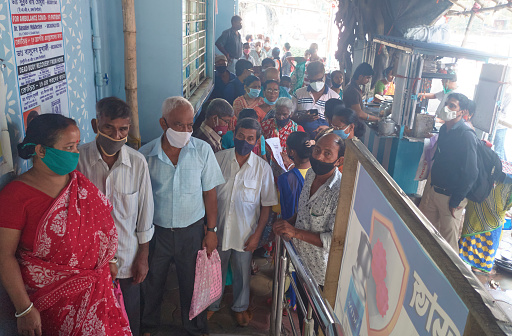 Kolkata, 07/15/2021: Crowd of large number of people waiting outside a covid-19 vaccine centre, happening in midst of coronavirus pandemic. Due to pandemic, people are wearing protective face mask.