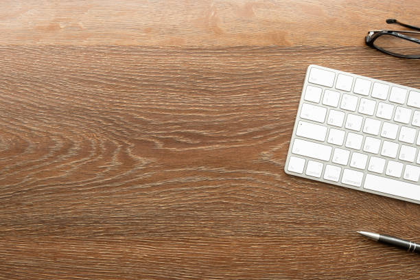 istock Wood office desk table with white computer keyboard and supplies. Top view with copy space, flat lay. 1330559431