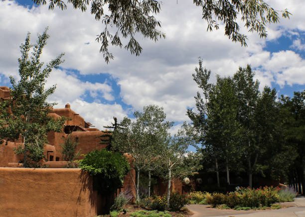 istock Southwestern adobe architecture under a blue sky with fluffy white clouds and surrounded and framed by trees 1330561144