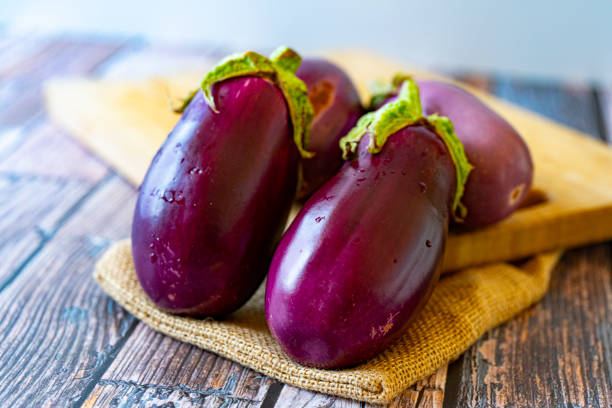 feche até berinjela orgânica fresca na mesa de madeira - eggplant farmers market purple agricultural fair - fotografias e filmes do acervo