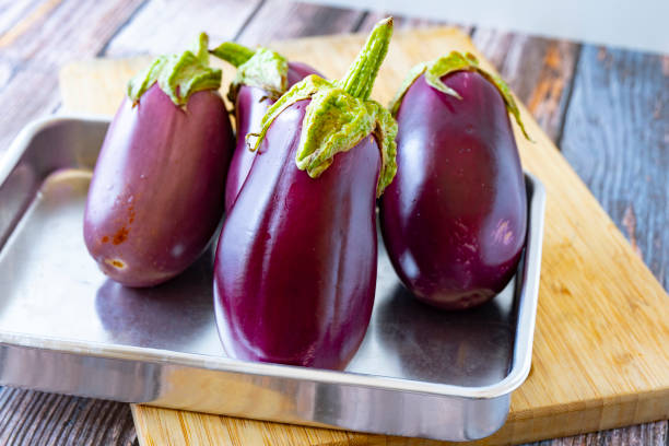 feche até berinjela orgânica fresca na mesa de madeira - eggplant farmers market purple agricultural fair - fotografias e filmes do acervo