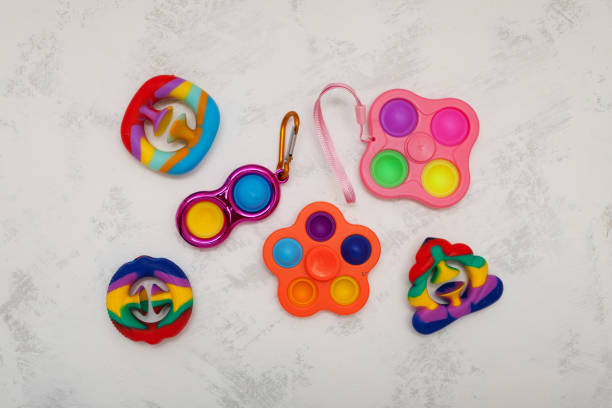 Different popular colorful children's toys (Spinner, Simple dimple, Pop it and Snapperz toys) on light grey background. Top view, copy space. Flat lay. Tap on bubble, play fingers