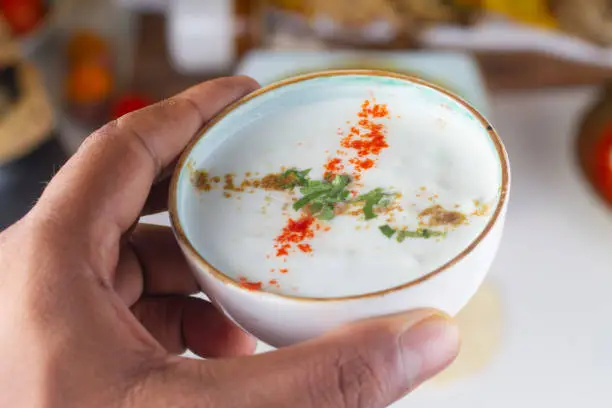 Photo of a person holding a curd bowl in hand isolated on light background.