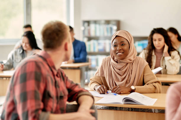 istock Happy black Muslim student talking to her classmate in the classroom. 1330567646
