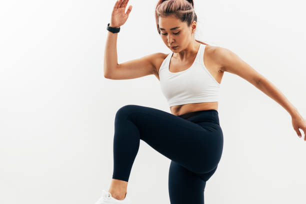 istock Young Asian woman doing warming up exercises against white wall 1330569381