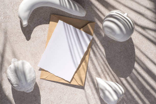 istock Summer conceptual still life with blank card mock-up and craft envelope with ceramic white fruits and palm leaf shadow on grunge beige concrete background. Flat lay, top view 1330571071