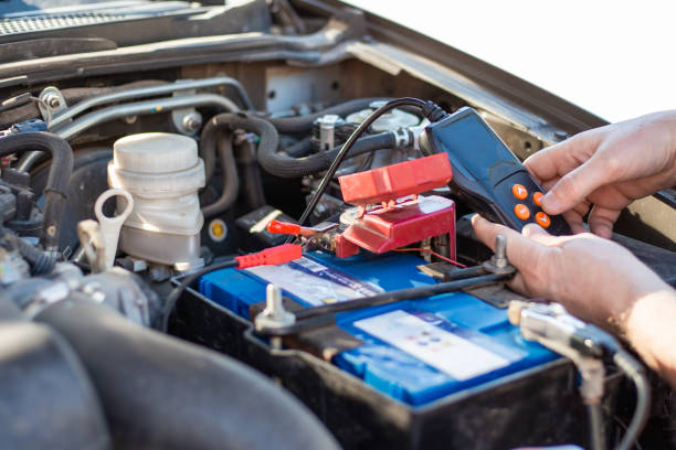 un uomo diagnostica una batteria di un'auto con un tester, da vicino. riparazione e sostituzione della batteria - battery replacement foto e immagini stock