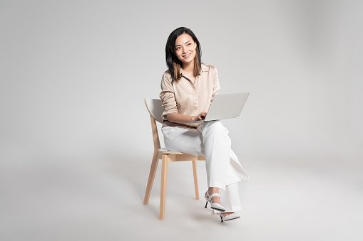 Portrait of an attractive young woman using her laptop in studio against a white background