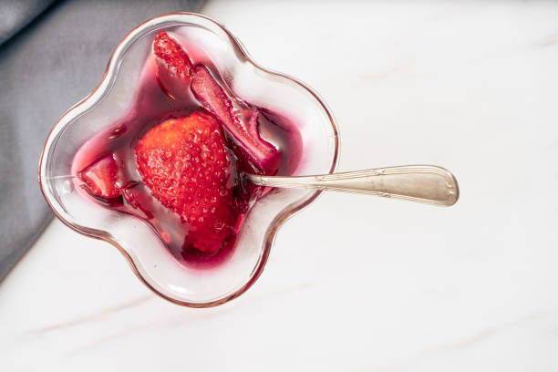 Raspberry jelly with fresh strawberries in a dessert glass.