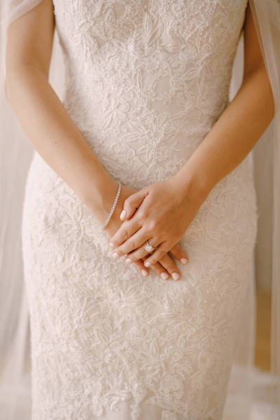 istock Bride in a wedding dress stands with her hands folded on her stomach 1330582199