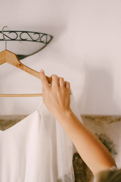 istock Bride hand holding a hanger with a wedding dress 1330582859