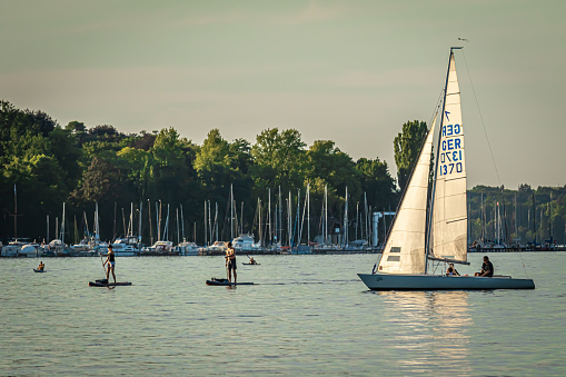 Berlin, Germany - July 24, 2019: People doing water sports in Wannsee Lake with sailing boats, paddle boards, kayaks