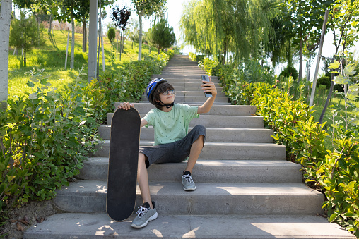 Happy Skater boy is doing selfie on the stairs in park