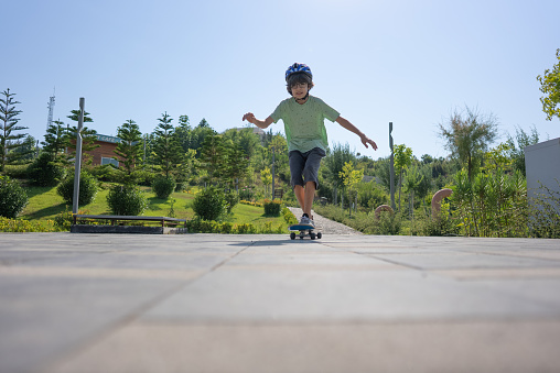 Happy boy learning skateboarding in park.