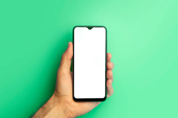 istock Empty smartphone in hand on colored blue banner background. Mockup phone with blank screen on minimal background 1330585872