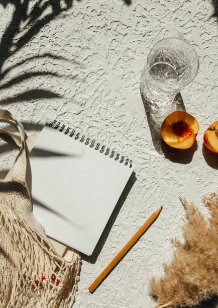 istock Summer flat lay on a concrete background. Notepad, peaches and an eco-friendly mesh shopping bag. Shadow and sunshine, sun. Summer travel fashion concept. 1330586199