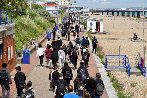 Young students walking home from school in Eastbourne Eastbourne, East Sussex, England UK July 4th 2021: School is out and local pupils walk along the seafront to enjoy what is left of the afternoon sunshine eastbourne pier photos stock pictures, royalty-free photos & images