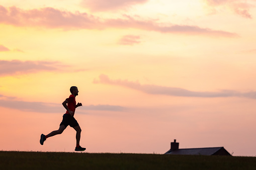 Silhouette of man running at sunset, wide view with copy space