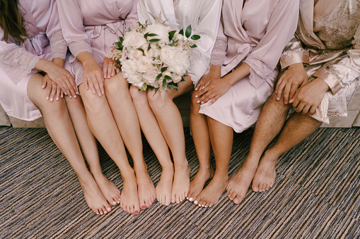 Bare feet of bridesmaids and bride with a bouquet of flowers. High quality photo