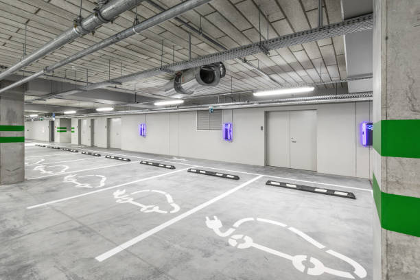 istock Empty public underground parking lot or garage interior with concrete stripe painted columns and signs. Electric car charging place. 1330590233
