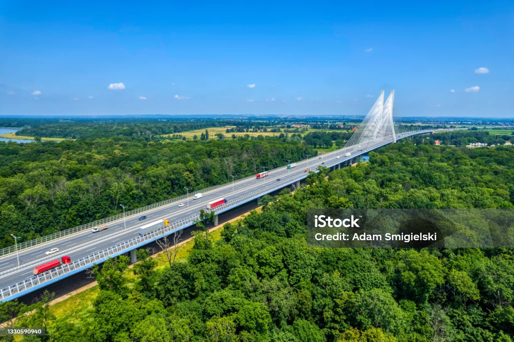 highway with the suspension bridge (aerial) highway crossing the green forest with the cable-stayed bridge on a horizon Poland Stock Photo