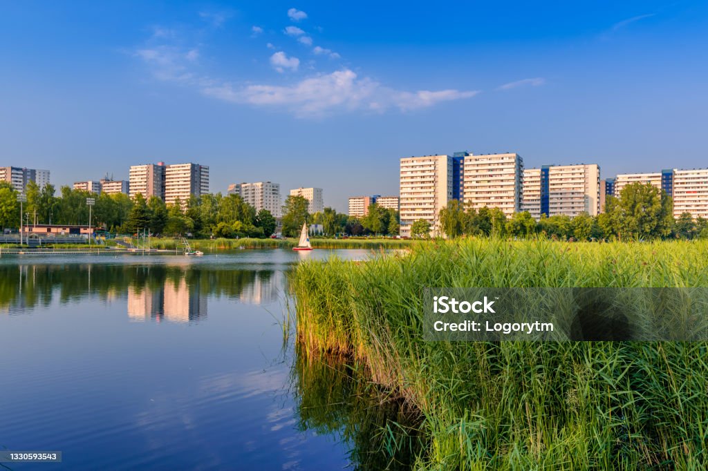 View at Tysiaclecie district in Katowice on a beautiful, sunny day, seen through the pond. Apartment buildings situated neat the lake against blue sky. Katowice Stock Photo