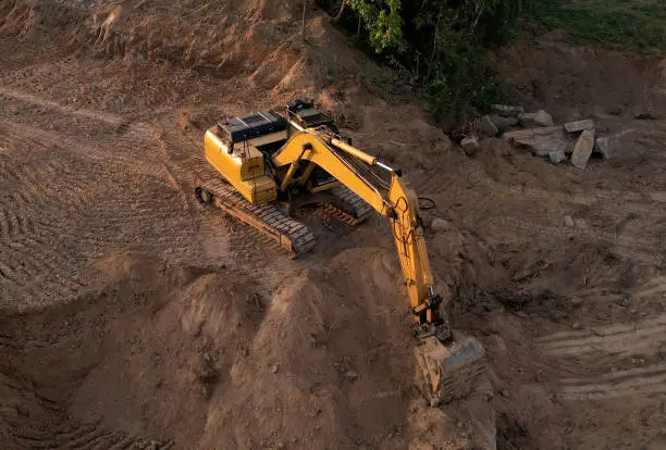 Excavator dig ground at construction site. Foundation pit for a multi-story building. Earth-moving heavy equipment. Arial view of the Digger on earthworks. Trench for laying external sewer pipes.