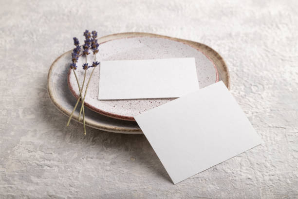 istock White paper invitation card, mockup with lavender on ceramic plate and gray concrete background. Blank, side view, still life, copy space. 1330595323
