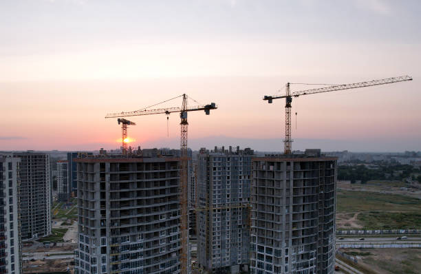 istock Tower cranes in action at construction site on sunset background 1330595324