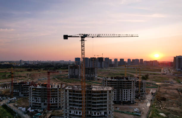 istock Tower cranes in action at construction site on sunset background 1330595332