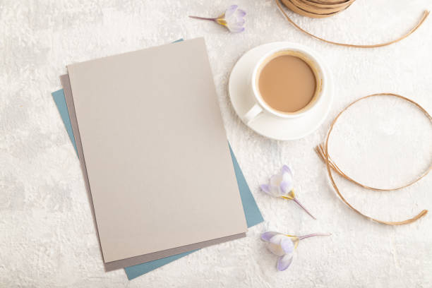 istock Gray paper sheet mockup with spring snowdrop crocus flowers and cup of coffee on gray concrete background. Blank, business card, top view, flat lay, copy space, still life. spring concept, close up. 1330596021