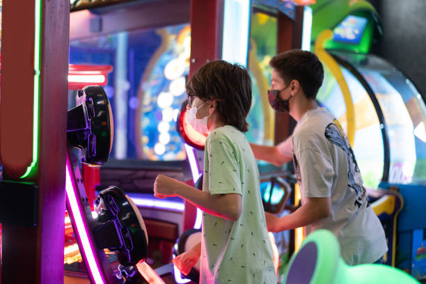 de jeunes amis heureux jouant à la machine de jeu d’arcade - amusement arcade photos et images de collection