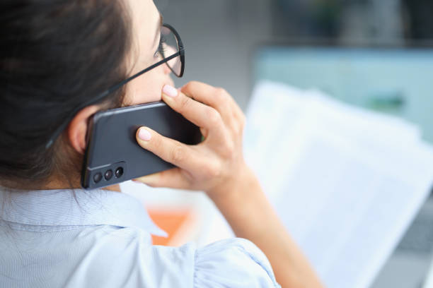 istock Businesswoman talking on smartphone and reading document solving corporate business problems 1330600383
