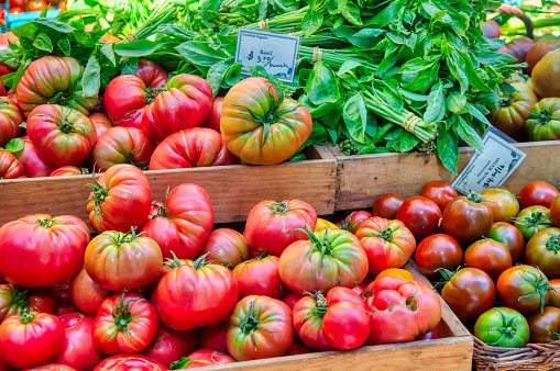 Closeup of many ripe red, small tomatoes on display farmers market shop store grocery Italy in wooden crate or box