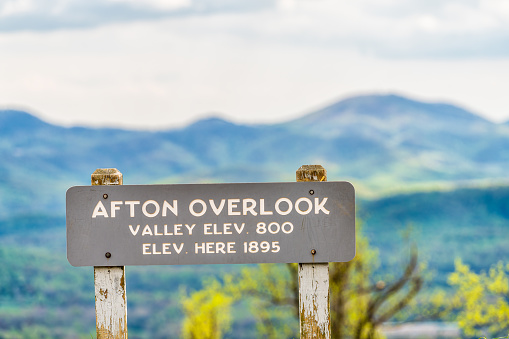 Overlook sign text for Afton valley and elevation at Blue Ridge parkway appalachian mountains in summer with nobody and scenic lush foliage bokeh background