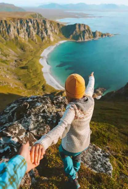 Photo of Couple traveling in Norway follow holding hands enjoying ocean beach aerial view