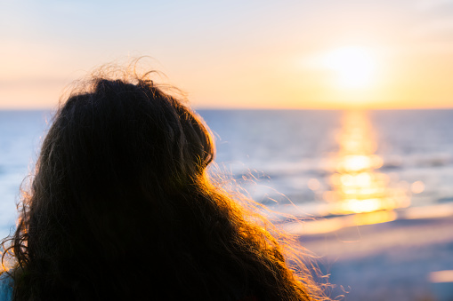 Silhouette of young female during sunset in Santa Rosa Beach Seaside, Florida gulf of mexico coast with backlight of sunlight and beach shore sun path