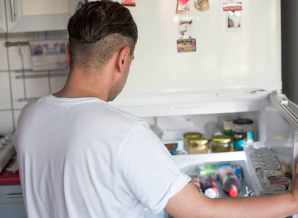 istock Young man standing near opended fridge at home kitchen 1330603396