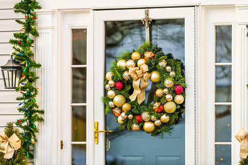 Christmas decoration wreath on door closeup on single family residential suburbs house in northern Virginia with glass windows and golden balls