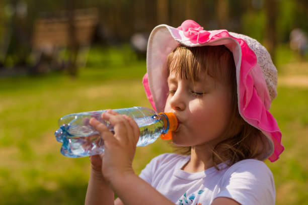 little girl greedily drinking water from a bottle in hot weather in summer a little girl greedily drinking water from a bottle in hot weather in summer young hot stock pictures, royalty-free photos & images